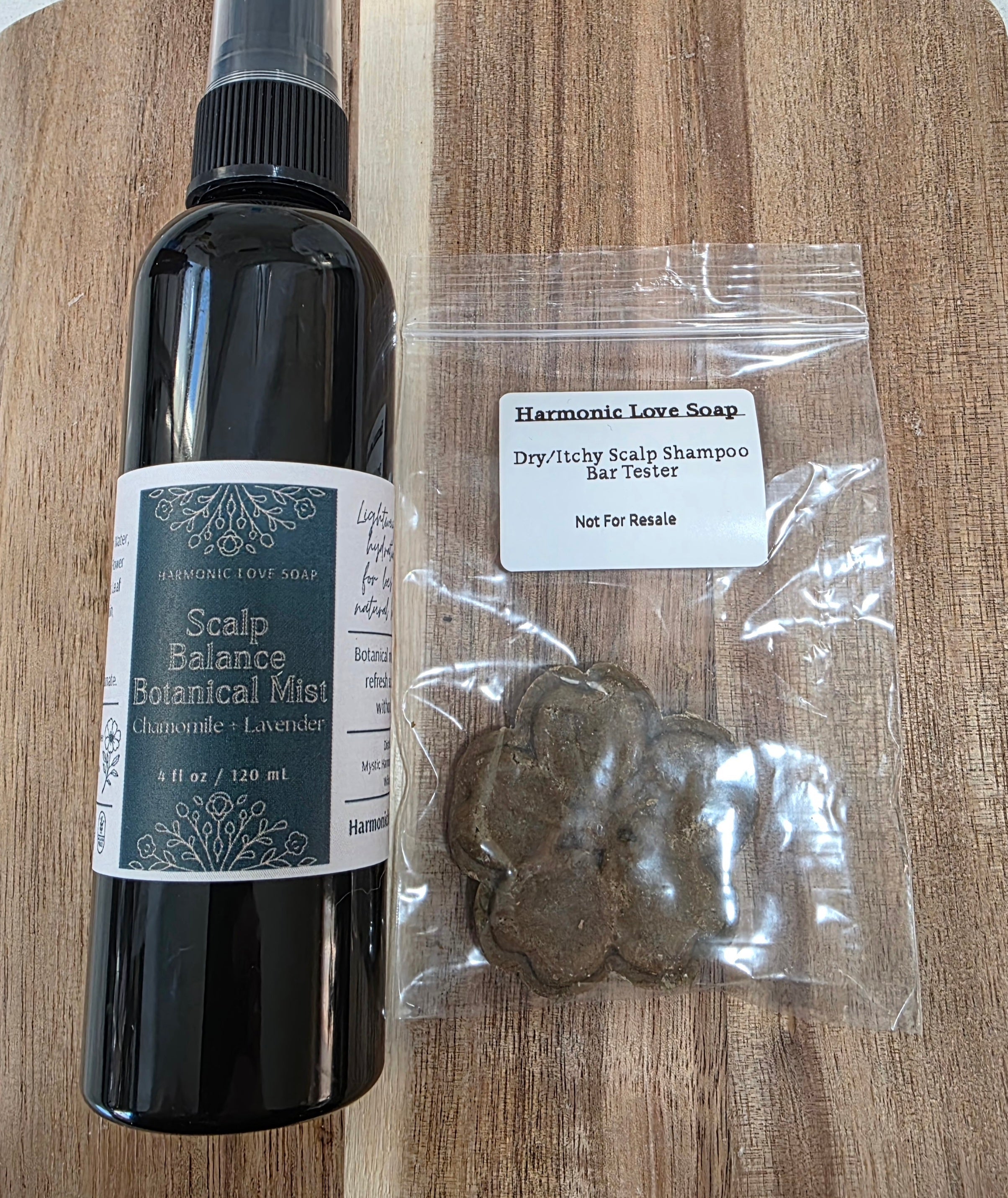 Bottle of Scalp Balance Botanical Mist and a package of Dry Itchy Scalp Shampoo Bar Tester on a wooden surface.